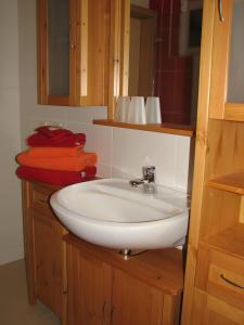 een badkamer met een witte wastafel en houten kasten bij Ferienhaus Enger in Beulwitz