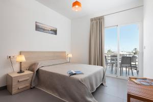 a bedroom with a bed and a view of a balcony at Apartaments S'Estanyol in La Savina