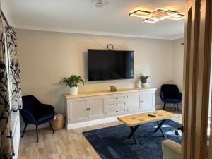 a living room with a tv and two chairs and a table at Birch View, Woodhall Spa in Woodhall Spa