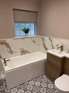 a bathroom with a tub and a toilet and a sink at Birch View, Woodhall Spa in Woodhall Spa +12 photos