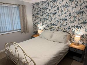 a bedroom with a white bed with a floral wallpaper at Birch View, Woodhall Spa in Woodhall Spa