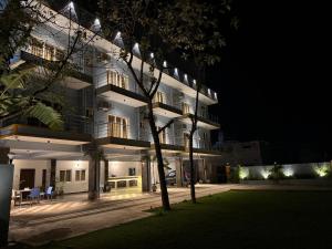 een groot wit gebouw 's nachts met een boom bij La Millionaire Resort in Auroville