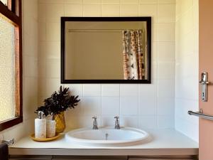 a bathroom with a sink and a mirror at Sandpiper Cottage in Fish Hoek