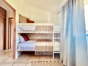 a bedroom with two bunk beds and a window at Sandpiper Cottage in Fish Hoek