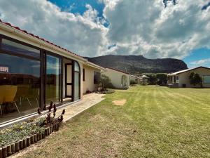 a house with a yard with mountains in the background at Sandpiper Cottage in Fish Hoek