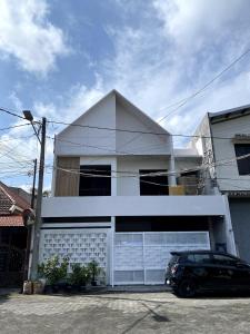 uma casa branca com um carro estacionado em frente dela em Sierra Villa Malang - Private Swimming Pool - 4 BR em Ngadipuro