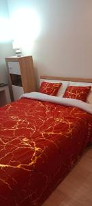 uma cama com um edredão vermelho e almofadas em Nastaran Nest em Oberhausen