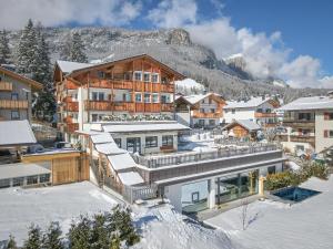 a building in the snow with a mountain in the background at Pensione Camoscio in La Villa