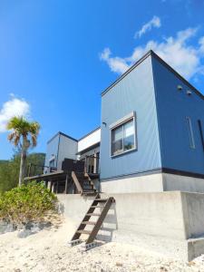 a blue house on the beach with a palm tree at isola villa amami in Tatsugo