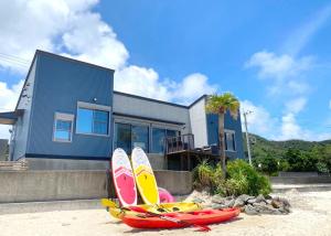 a group of surfboards sitting on the beach in front of a house at isola villa amami in Tatsugo