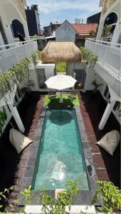 a small swimming pool with an umbrella and a table at Azure Suites in Dalung