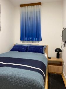 a bedroom with a bed with blue sheets and a window at Apartman 8 Panorama sa garažom in Bjelašnica