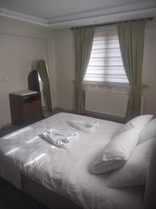 a bed with two white towels on it with a window at Living House in Salihli
