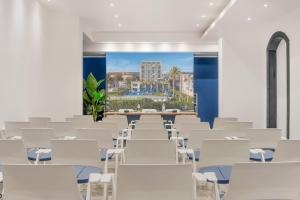 a room with white chairs and a wall with a painting at Hotel Excelsior in Marina di Massa +120 photos