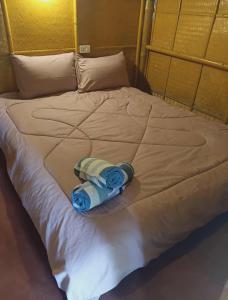 Una cama blanca con una toalla azul. en Bambu hut, en Phra Ae beach