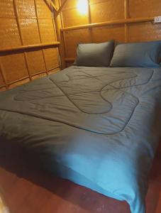 1 cama azul grande en una habitación con pared en Bambu hut, en Phra Ae beach 4 fotos más