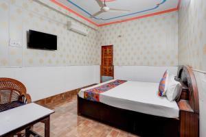 a bedroom with a bed and a tv on the wall at FabHotel Jyotish Bhawan in Ayodhya