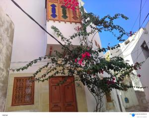 a building with a red door and a clock tower with pink flowers at Dar Baaziz 2 in Sousse
