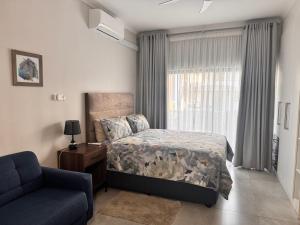 a bedroom with a bed and a couch and a window at Cozy-corner in Gaborone +15 photos