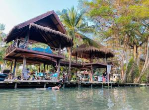 a man swimming in the water in front of a resort at Latehouse bar อัมพวา in Ban Nong Chaeng