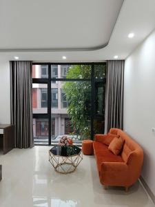 a living room with an orange couch and a large window at Ha Noi Smile Home in Ðình Loan