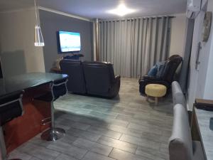 een woonkamer met een tv, een bureau en stoelen bij Muize at Sea in Marina da Gama