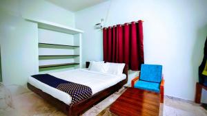 ein Schlafzimmer mit einem Bett und einem blauen Stuhl in der Unterkunft Naadi Grand Inn in Thanjavur + 52 Fotos