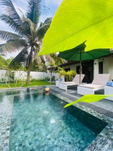 uma piscina com um guarda-sol amarelo e cadeiras e uma casa em Villa 2A em Matara