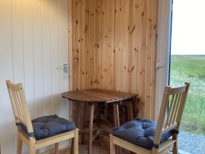 a wooden table and two chairs sitting next to a window at Shepherd's hut 2 at Braebost Croft in Portree +6 photos