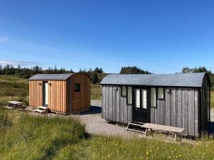 two small buildings in a field with a bench at Shepherd's hut 2 at Braebost Croft in Portree