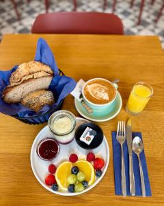 a table with a breakfast plate of bread and fruit at ZIEGELHÜSI Hotel - Self CheckIn, Stettlen bei Bern in Bern