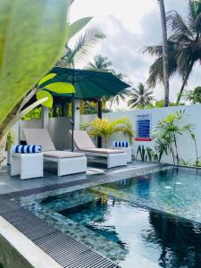 ein Swimmingpool mit zwei Stühlen und einem Sonnenschirm in der Unterkunft Villa 2A in Matara