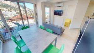 a dining room with a table and green chairs at Nice 2P with terrace and side sea view in Menton