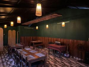 um restaurante com mesas e cadeiras de madeira e um violão em Aruvi Mountain Villa Vagamon by VOYE HOMES em Vagamon