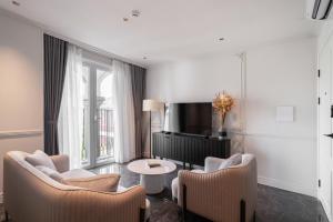 ein Wohnzimmer mit zwei Stühlen und einem Fernseher in der Unterkunft AMANA Boutique Hotel - Thân Văn Nhiếp in Ho-Chi-Minh-Stadt