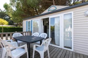 a patio with a table and chairs on a deck at Camping Les Maraises in Saint-Martin-de-Ré