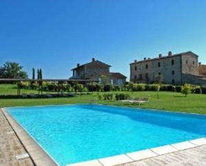 a large blue swimming pool in front of a building at La terrazzina nel borgo apt dimora storica toscana pool&garden in Lano