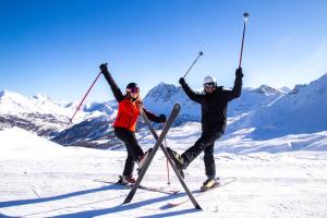 zwei Personen auf Skiern, die ihre Stöcke an einem Berg festhalten in der Unterkunft SOWELL FAMILY Vars in Vars
