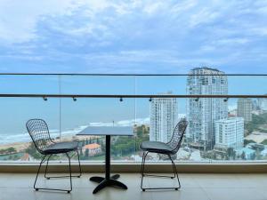 头顿The Sóng Vũng Tàu Infinity Pool Apartment - Hồ Bơi Vô Cực的窗前摆放着两把椅子和一张桌子。 更多144张照片