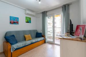 a living room with a blue couch and a window at rentafive - Nuevo - Centro - A/C in Santa Pola