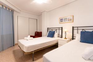 a bedroom with two beds and a chair at rentafive - Nuevo - Centro - A/C in Santa Pola