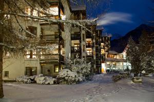 a building with snow in front of it at night at Schweizerhof Ferienwohnungen Lenzerheide 1 in Lenzerheide