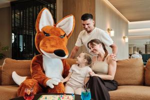 泽勒兹纳·鲁达OREA Resort Horizont Šumava的一名男子、一名女子和一个孩子坐在一个毛绒玩具旁边。