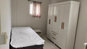 een slaapkamer met een bed en een grote witte kast bij Dormitorio e WC privativo semanal in Valinhos
