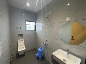 un bagno con lavandino, WC e specchio di Hotel Abhishek Pride - Shani Shinganapur a Godhegaon