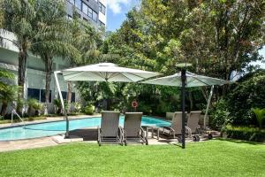 a group of chairs and umbrellas next to a pool at Garden Court Milpark, Johannesburg in Johannesburg