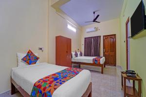 a hotel room with two beds and a television at FabHotel Martine's Residency - French Colony, 5 Mins from Rock Beach in Puducherry
