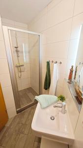 a white bathroom with a shower and a sink at Ferienwohnung Ostseeblick in Breege +4 photos