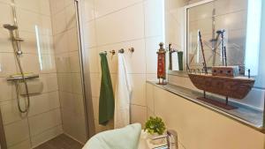 a bathroom with a shower and a sink with a boat on a shelf at Ferienwohnung Ostseeblick in Breege