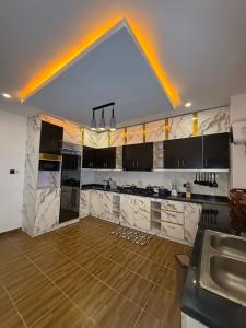 una grande cucina con banconi bianchi e pavimento in legno di Quantum Havens Apartment - PARIS ad Akure Altre 63 foto